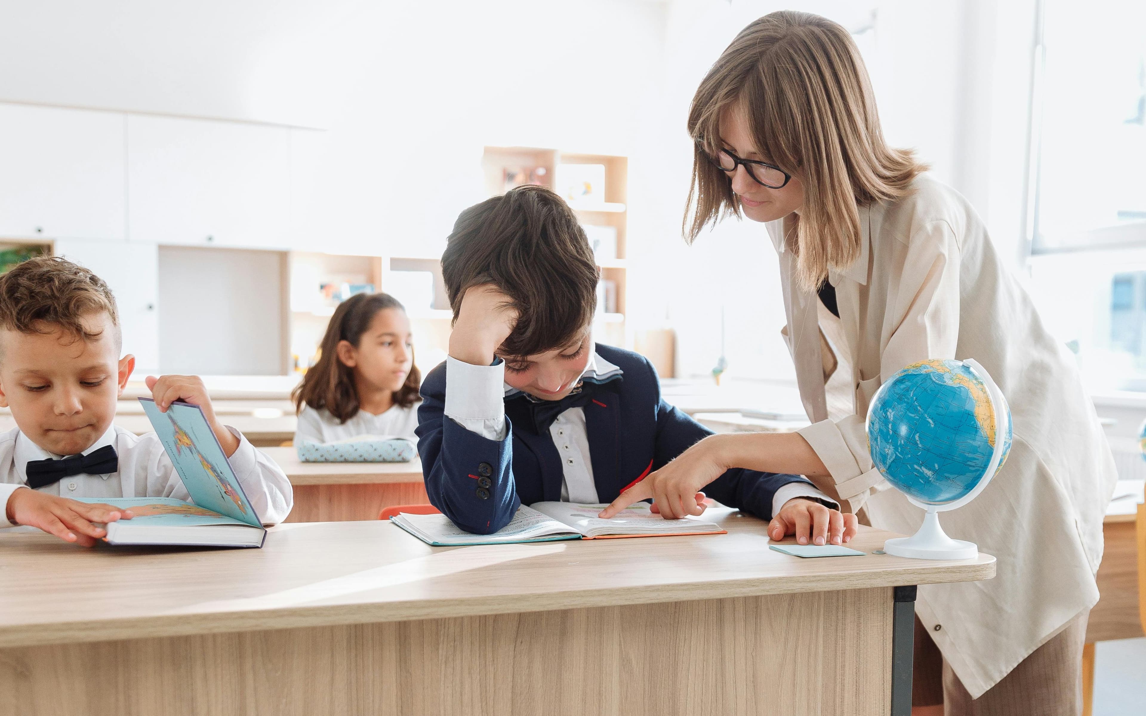 Învățătoarea îi explică elevului ce scrie în carte